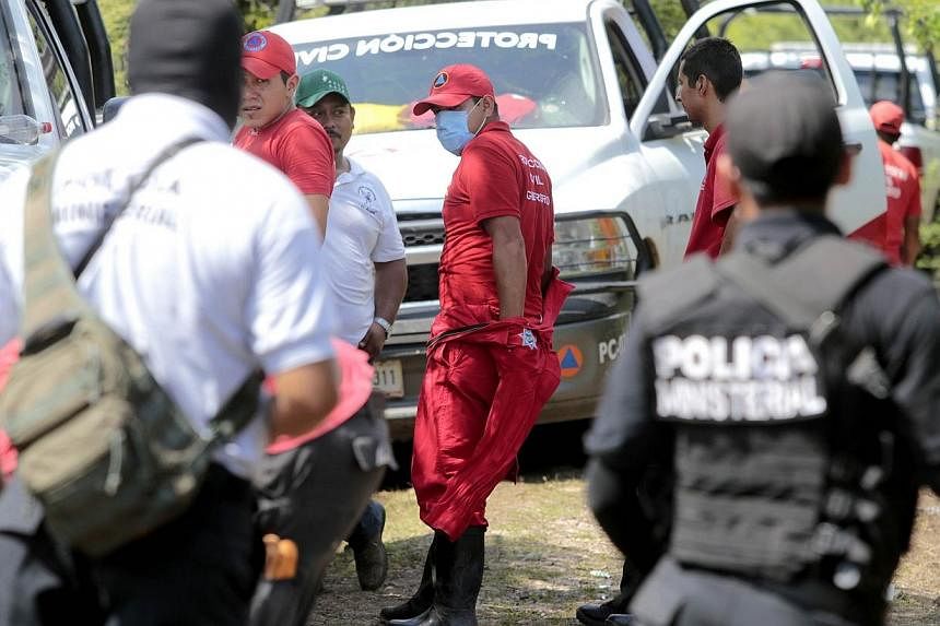 Mexican police officers and members of the civil protection remain in the site where a mass grave was found in Pueblo Viejo, in the outskirts of Iguala, Guerrero state, Mexico, on Oct 5, 2014.&nbsp;Hitmen linked to police have confessed to murdering 