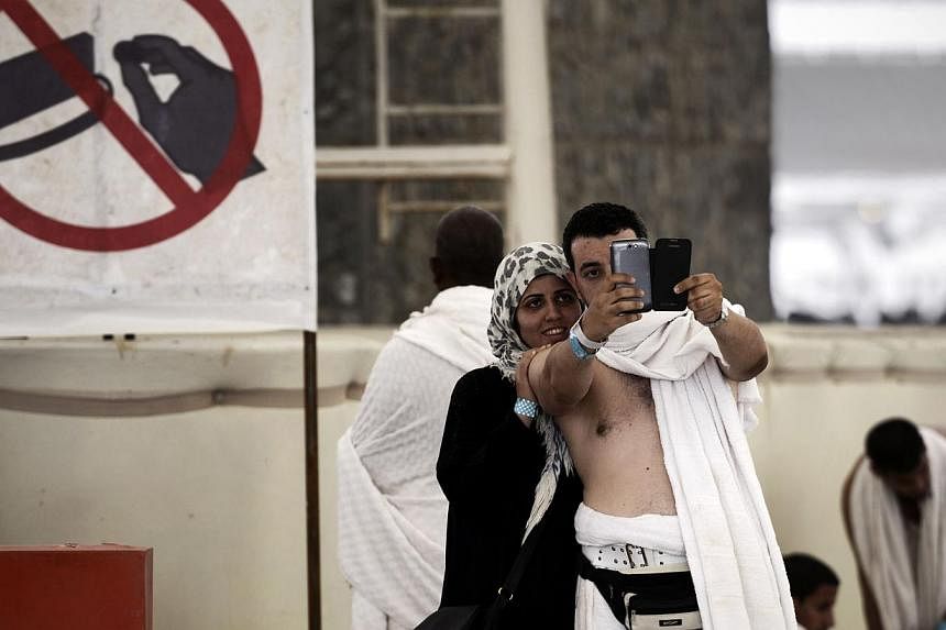 Muslim pilgrims pose for a selfie during the "Jamarat" ritual, the stoning of Satan, in Mina near the holy city of Mecca, on Oct 4, 2014. -- PHOTO: AFP