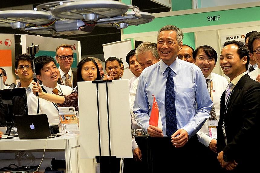Prime Minister Lee Hsien Loong getting a&nbsp;demonstration of the flying robot waiter at the launch of National Productivity Month.&nbsp;-- ST PHOTO:&nbsp;JAMIE KOH