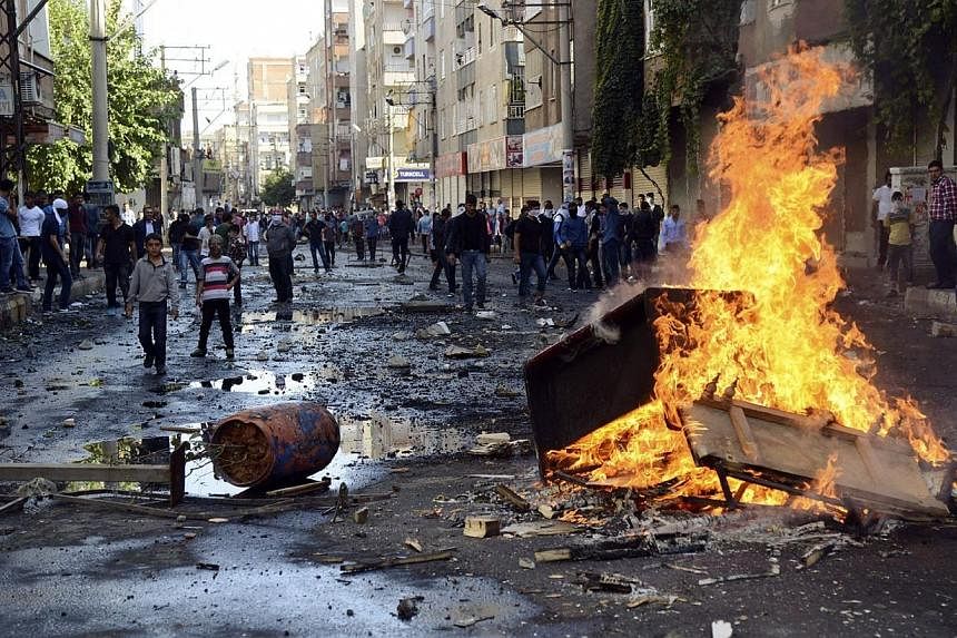 Kurdish protesters set fire to a barricade set up to block the street as they clash with riot police in Diyarbakir on Oct 7, 2014.&nbsp;In a measure unprecedented in the last years, the Turkish army has deployed in the streets of the cities of Diyarb