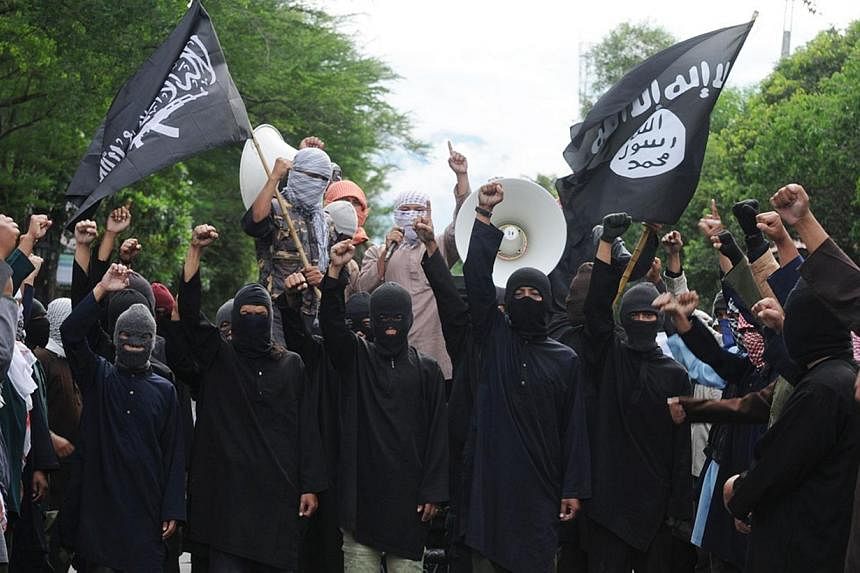 In this file photograph taken on June 9, 2013, masked Indonesian Islamic militants waving the flag of ISIS stage a rally against Syria's President Bashar al-Assad in Solo, central Java island, where they declared their preparedness to join the war in