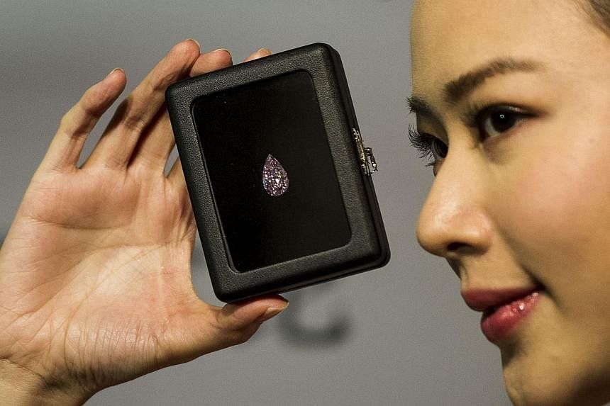 A model showcases a 8.41 carat pear-shape internally flawless fancy vivid pink diamond at a Sotheby's gallery in Hong Kong on Sep 18, 2014. -- PHOTO: AFP