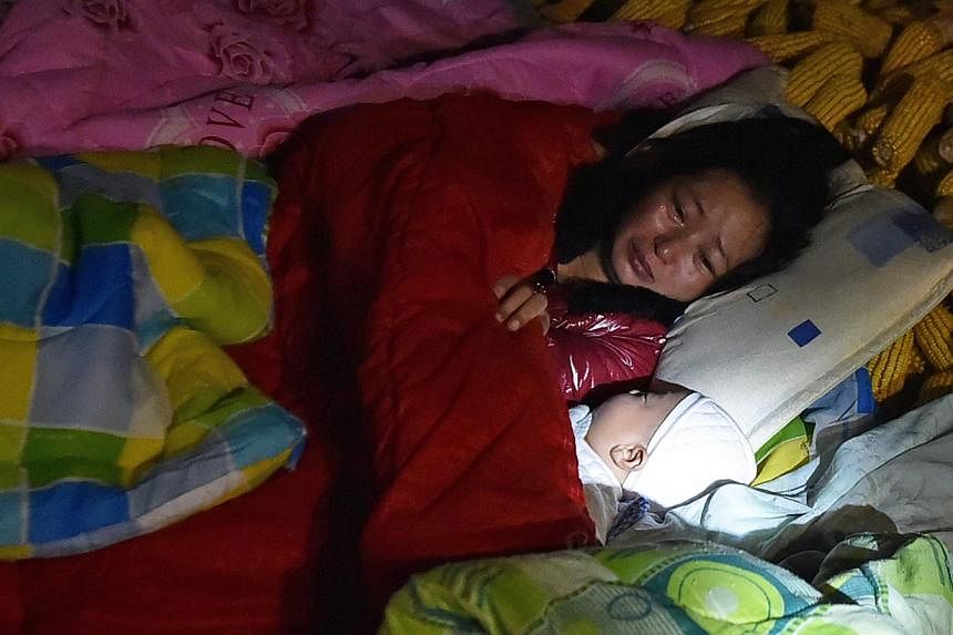 Dao Yanling, a villager from Jinggu county, spends the night outdoors with her three-month-old son following a strong earthquake that hit China's south-west Yunnan province. So far, one person has been killed and more than 300 people injured as well 