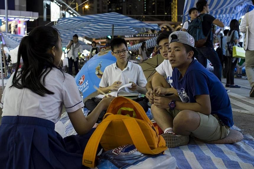 Secondary school students do their homework at a protest site, as protesters occupy a main road at Causeway Bay shopping district, in Hong Kong on Oct 8, 2014. -- PHOTO: REUTERS