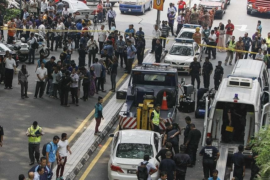 People watch as police tow away a damaged white sedan (centre in foreground) at the scene of a grenade attack outside a shopping centre at Bukit Bintang in Kuala Lumpur on Oct&nbsp;9, 2014.&nbsp;An explosion outside a Kuala Lumpur pub on Thursday tha