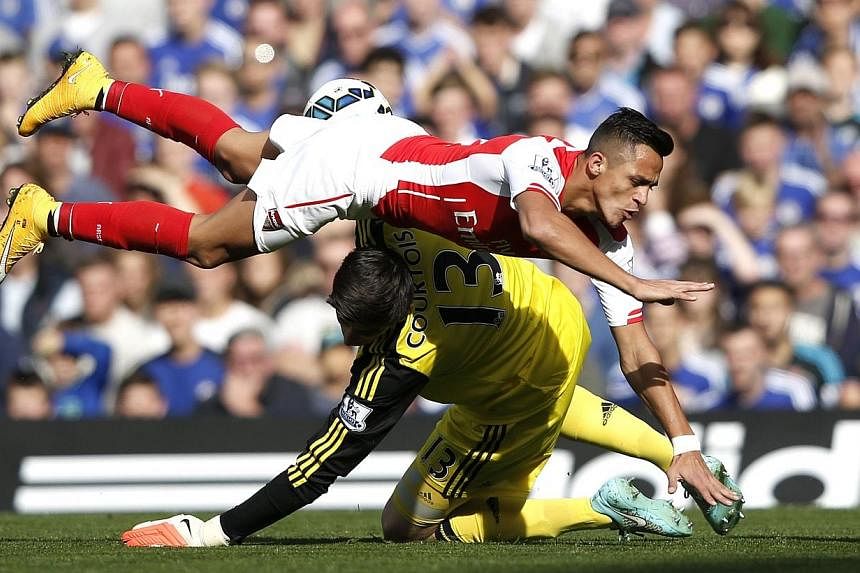 Arsenal's Chilean striker Alexis Sanchez (top) collides with Chelsea's Belgian goalkeeper Thibaut Courtois during the English Premier League football match between Chelsea and Arsenal at Stamford Bridge in London on Oct 5, 2014.&nbsp;Chelsea observed