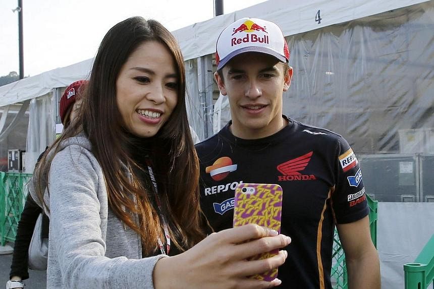 Honda MotoGP rider Marc Marquez (right) of Spain poses for a photo with a fan in the paddock area at the Twin Ring Motegi circuit ahead of Sunday's Japanese Grand Prix in Motegi, north of Tokyo on Oct 9, 2014.&nbsp;Marquez can retain his MotoGP title