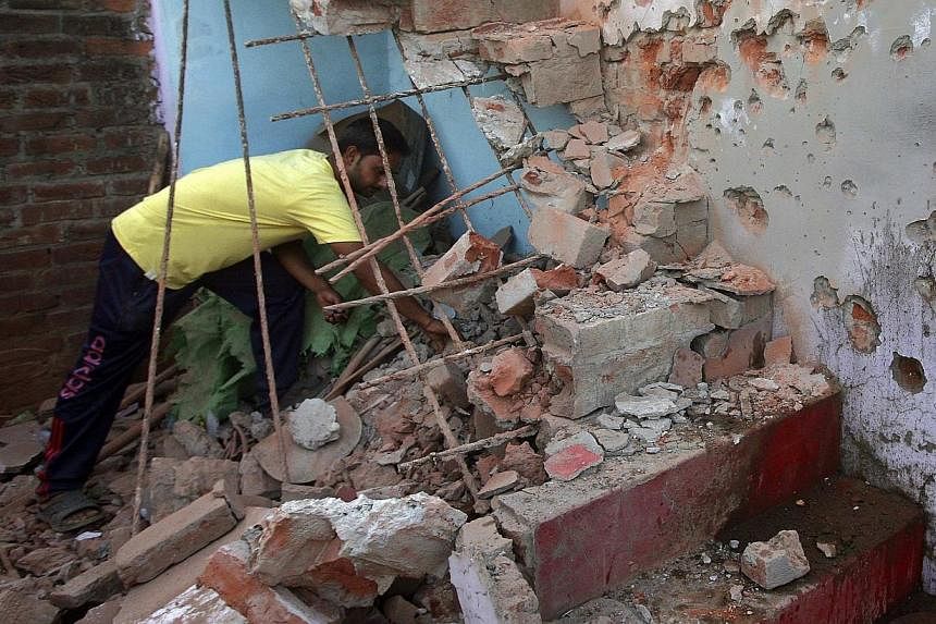 An Indian villager clears the debris from his house, which locals said was damaged by firing from the Pakistan side of the border, at Trewa village near Jammu on Oct 7, 2014.&nbsp;India's defence minister accused Pakistan on Thursday of making unprov