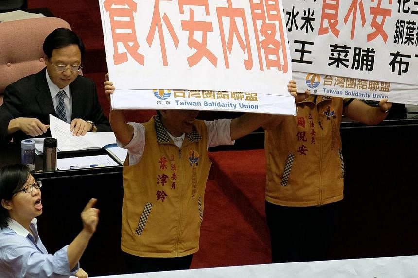 Opposition lawmakers display placards demanding Premier Jiang Yih-hua (left) apologise for the gutter oil scandal before his speech during the new parliament session in Taipei on Sept 12, 2014.&nbsp;The head of a leading Taiwanese food company resign