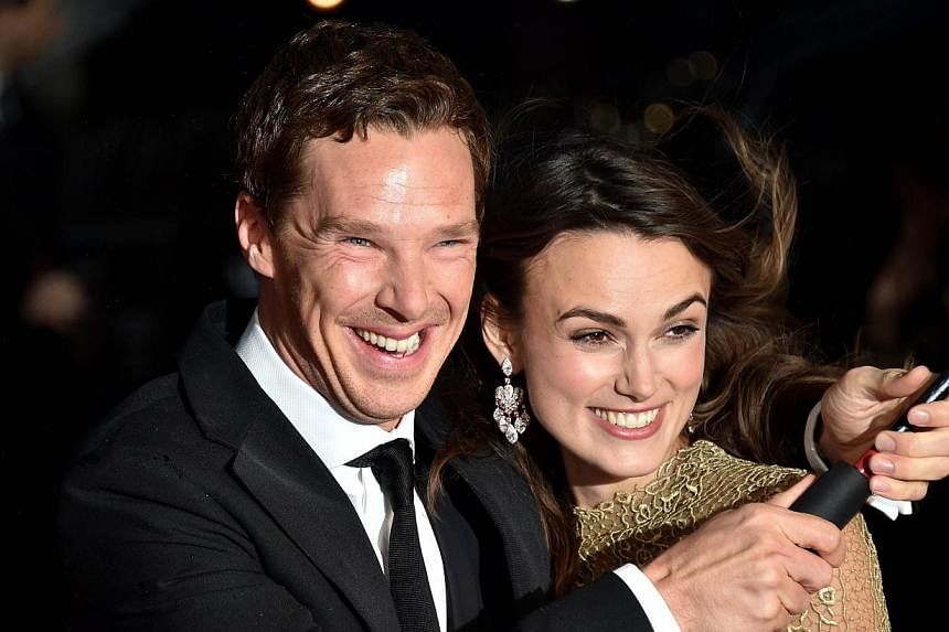 British actors Keira Knightley (right) and Benedict Cumberbatch brave the weather as they pose for pictures during the BFI London Film Festival's premiere of 'The Imitation Game at the Odeon Leicester Square in central London on Oct 8, 2014. -- PHOTO