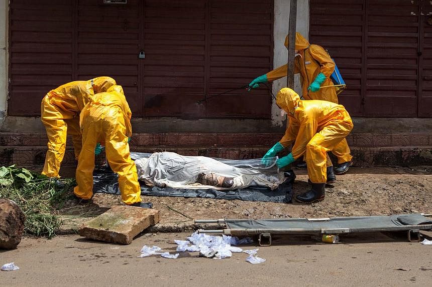Volunteers pick up bodies of people who died of the Ebola virus on Oct 8, 2014 in Freetown, Sierra Leone.&nbsp;The United States will begin screening passengers arriving at US airports from West Africa for fever starting this weekend, US officials sa
