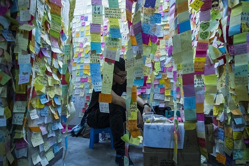 Pro democracy protester is seen surrounded by post it with encouragement at Admiralty district during the rally after government called off the talks with students on Oct 10, 2014 in Hong Kong. -- PHOTO: AFP