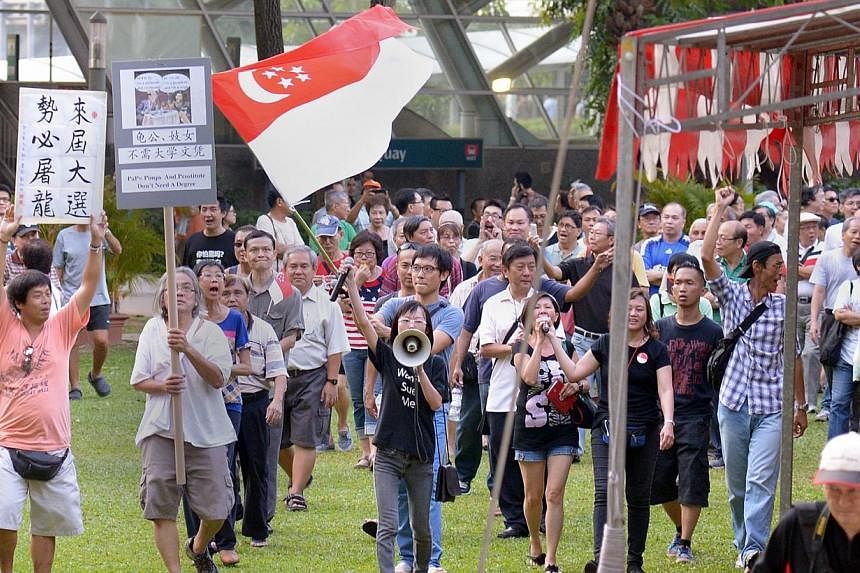 Han Hui Hui (with loudspeaker) and Roy Ngerng (carrying state flag) with supporters at the Return Our CPF rally, marching round the park at the rally on Sept 27, 2014. -- ST PHOTO: LIM SIN THAI