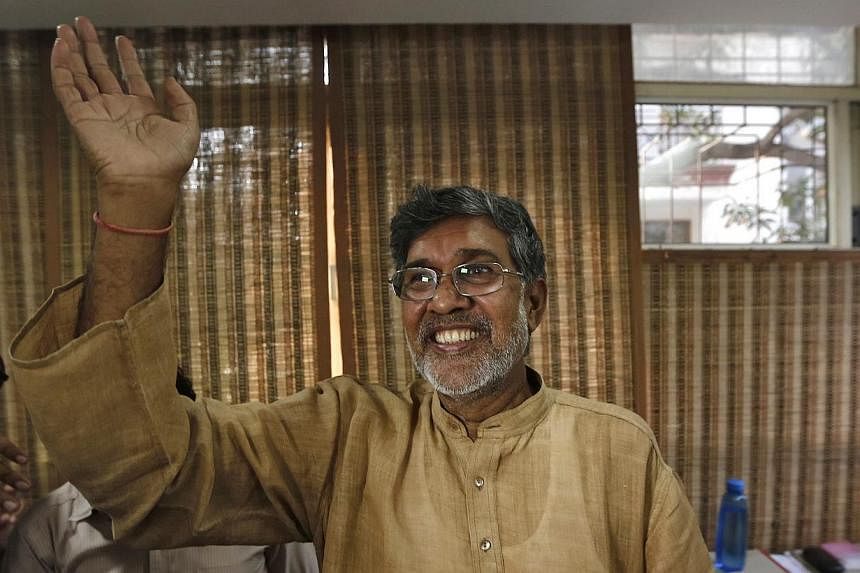 Indian children's right activist Kailash Satyarthi waves to the media at his office in New Delhi on Oct 10, 2014. Mr Satyarthi, 60, and Malala Yousafzai, 17, from Pakistan, were jointly awarded the Nobel Peace Prize on Friday. -- PHOTO: REUTERS