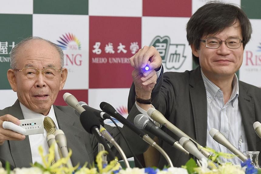 Meijo University Professor Isamu Akasaki (left) and Nagoya University Professor Hiroshi Amano (right) hold a prototype (left) and a new blue light-emitting diode (LED) during a press conference at Nagoya University in Nagoya, central Japan on Oct 10,