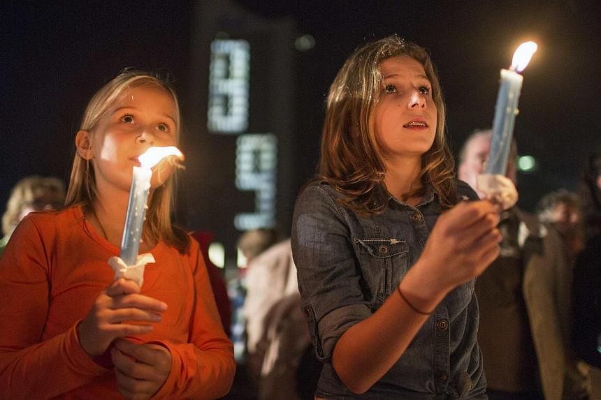 Girls hold candles at Augustusplatz square in front of a building showing the number 89 in Leipzig on Oct 9, 2014. Celebrations on Thursday marked the 25th anniversary of a historic demonstration in the eastern German city, when 70,000 East German ci