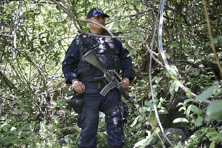 A state police officer stands guard near a mass grave that was found days ago at the foot of a hill outside of Iguala, Guerrero state, Mexico on Oct 09, 2014.&nbsp;Mexican authorities have found four new mass graves in the investigation into the disa