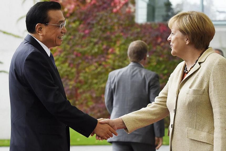 German Chancellor Angela Merkel (right) shakes hands with Chinese Prime Minister Li Keqiang upon his arrival at the Chancellery in Berlin on Oct 9, 2014. -- PHOTO: AFP&nbsp;