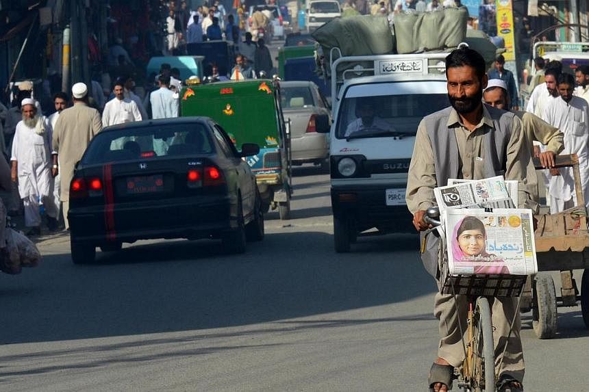 A Pakistani vendor carries morning newspapers with the headline of Nobel Peace Prize winner, child education activist Malala Yousafzai on his bicycle in Malala's hometown Mingora in north-western Swat valley on Oct 11, 2014. -- PHOTO: AFP