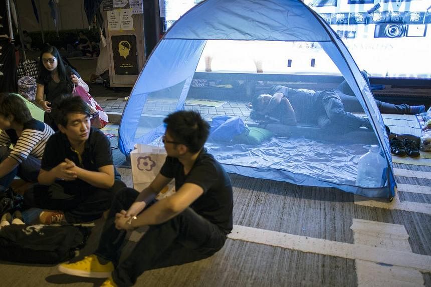 A protester of the Occupy Central movement sleeps in a tent as pro-democracy protesters continue blocking areas around the government headquarters building in Hong Kong on Oct 11, 2014. -- PHOTO: REUTERS