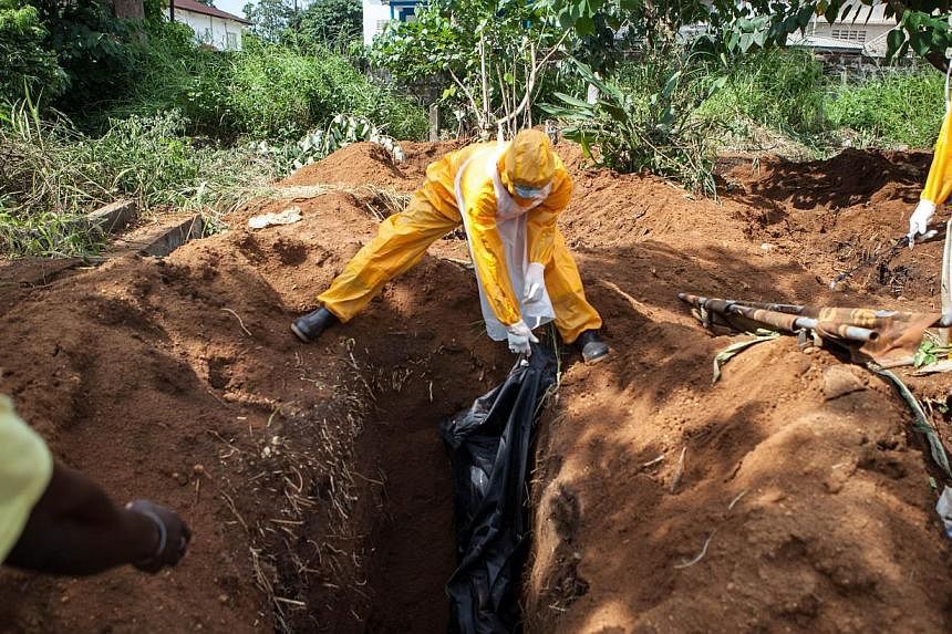 A team of funeral agents specialised in the burial of victims of the Ebola virus put a body in a grave at the Fing Tom cemetery in Freetown, Sierra Leone on Oct 10, 2014. Pledges of financial aid to fight Ebola have fallen far short of the US$1 billi