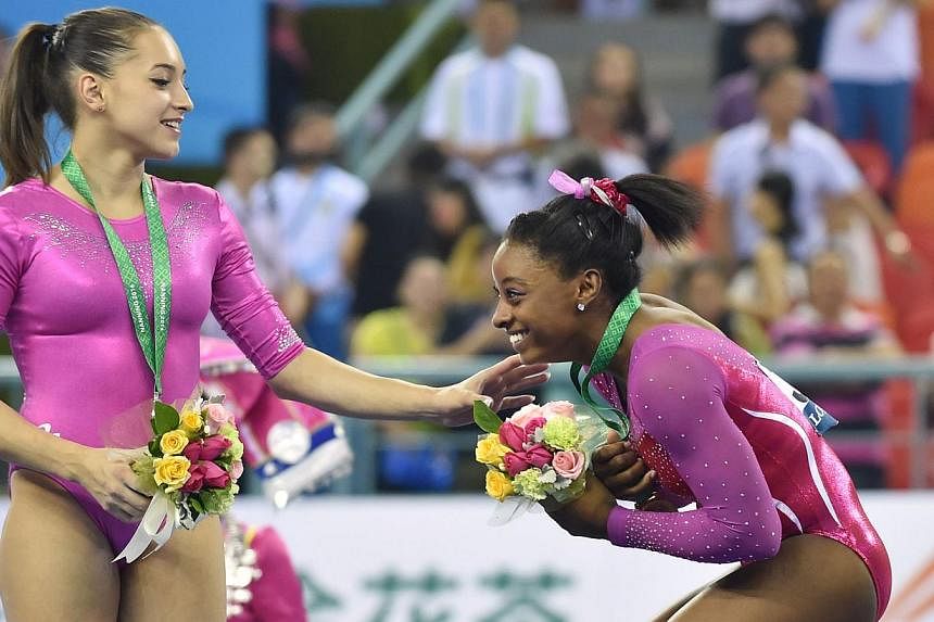 Winner Simone Biles of the US (right) and second placed Larisa Andreea Iordache of&nbsp;Romania&nbsp;react from a bee buzzing past during the awards ceremony of the women's all-around final at the gymnastics world championships in Nanning on Oct 10, 
