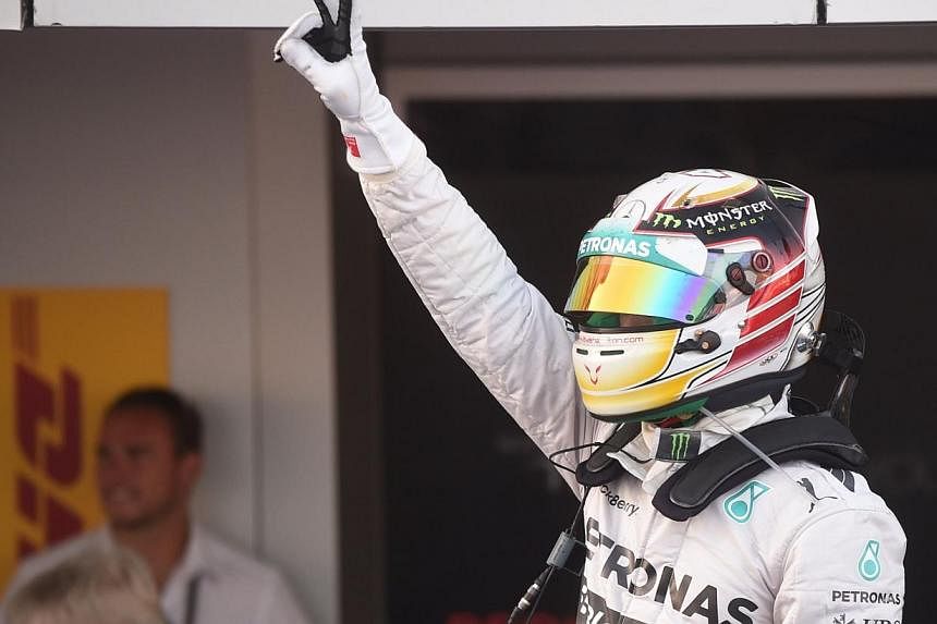 Mercedes' British driver Lewis Hamilton raises his arm after winning the inaugural Russian Formula 1 Grand Prix at the Sochi Autodrom in Sochi on Oct 12, 2014. -- PHOTO: AFP