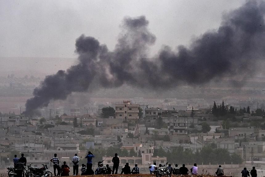 Kurdish people look at smoke rising from the Syrian town of Ain al-Arab, known as Kobane by the Kurds, from the Turkish-Syrian border, on Oct 11, 2014 in Mursitpinar, Sanliurfa province.&nbsp;The Islamic State in Iraq and Syria (ISIS) group poured in