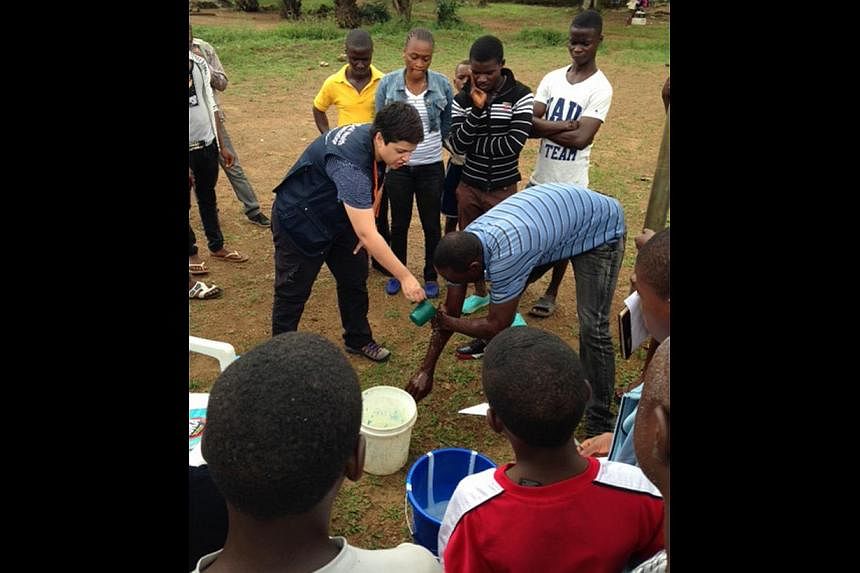 Associate Professor Fisher in Liberia with children separated from their parents - possible Ebola victims - but who have tested negative. Nurse Sharon Salmon shows villagers how to wash their hands with the right mix of chlorine and water to disinfec