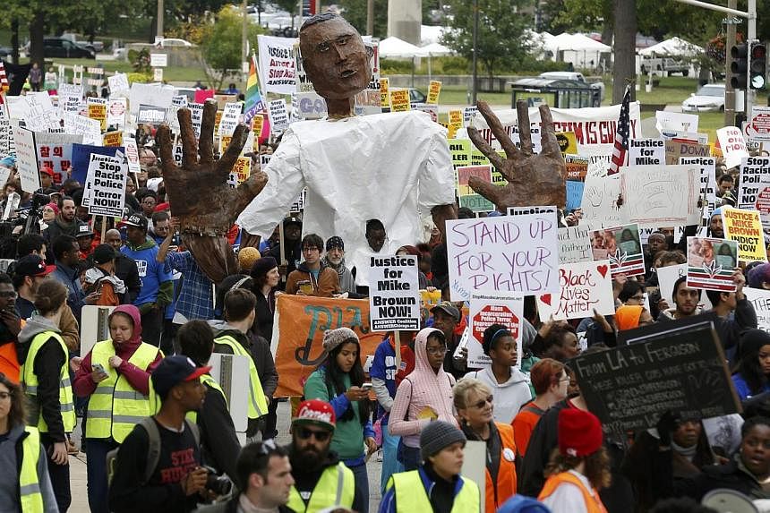 Protesters march in a rally with a paper mache representation of Michael Brown with his hands up, in St Louis, Missouri, on Oct 11, 2014. Thousands of protesters marched through St Louis on Saturday as part of a weekend of demonstrations against poli