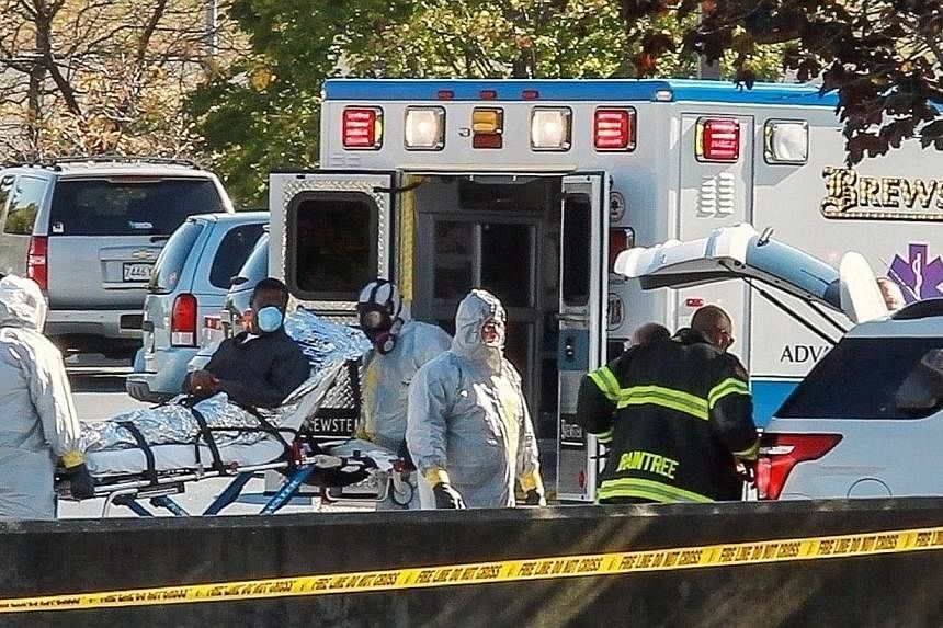 Ambulance workers wearing protective gear load a patient with possible Ebola symptons into the back of an ambulance at the Harvard Vanguard facility in Braintree, Massachusetts Oct 12, 2014. -- PHOTO: REUTERS