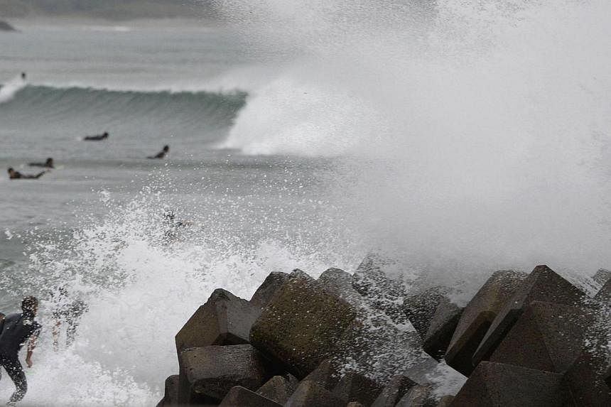Waves crash as Typhoon Vongfong approaches Japan's main islands while surfers try to ride a wave at Eguchihama Beach in Hioki, Kagoshima prefectureon Oct 12, 2014. -- PHOTO: REUTERS