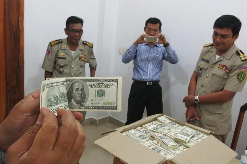 Police and court officials examine notes from a seized haul of US$7.16 million (S$9.1 million) in counterfeit hundred-dollar bills, in Battambang on Sept 30, 2014. -- PHOTO:REUTERS