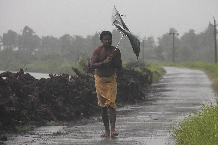 A man struggles with an umbrella in strong winds and rain caused by Cyclone Hudhud in Gopalpur in Ganjam district in the eastern Indian state of Odisha on Oct 12, 2014.&nbsp;A major relief operation was under way on Monday after the cyclone pounded I