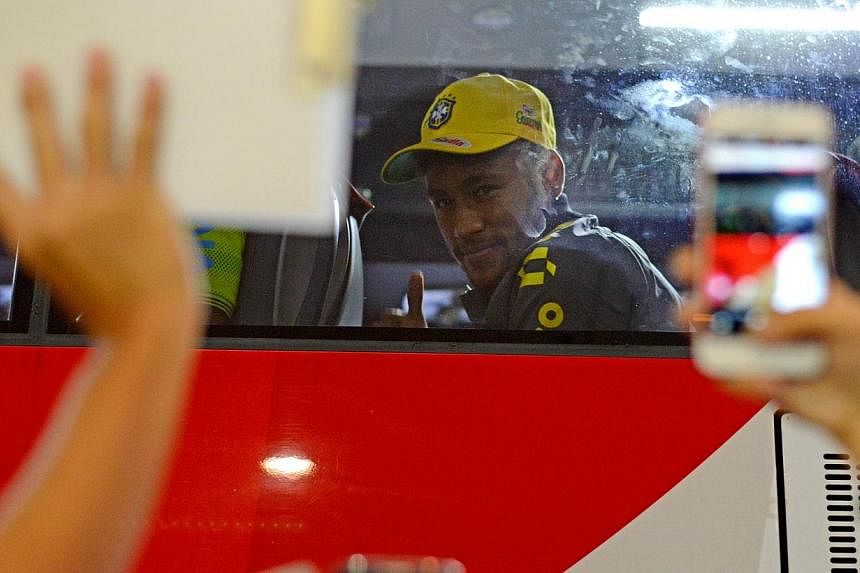 Brazil National player Neymar gestures to fans at Changi Airport together with his teammates in Singapore on Oct 12, 2014.&nbsp;Fans hoping to catch a glimpse of superstars Neymar and Kaka in action will have to wait until Tuesday's game against Japa
