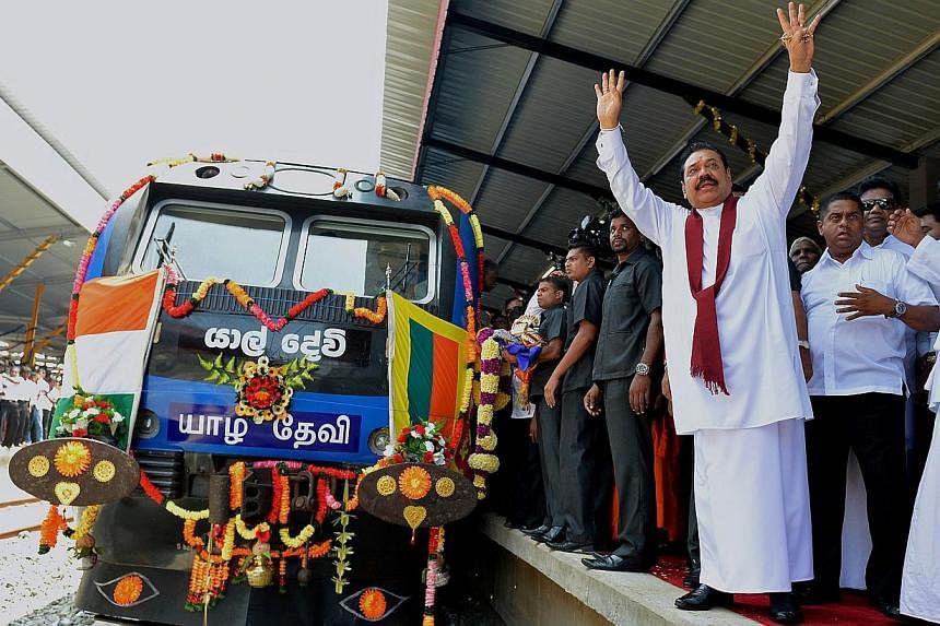 Sri Lankan President Mahinda Rajapakse raises both hands to acknowledge cheers at the rebuilt Jaffna railway station on Oct 13, 2014, as he arrives to officiate the resumption of rail services to the war-battered region.&nbsp;More than two decades af