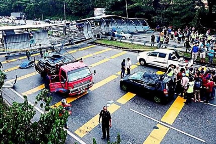 Motorists gathering to look at the collapsed roof and railings of a pedestrian bridge that flew off due to a thunderstorm along the Pasir Gudang Highway in Johor Baru, Malaysia, on Oct 12, 2014. -- PHOTO: THE STAR/ASIA NEWS NETWORK