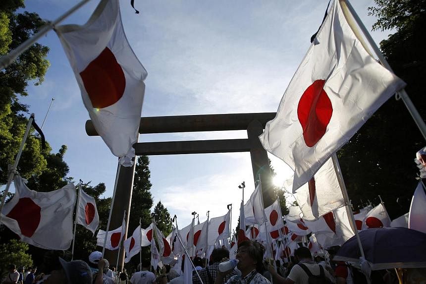 Members of nationalist movement Ganbare Nippon hold Japanese national flags under the huge Torii gate at the Yasukuni shrine while paying tribute to the war dead in Tokyo on Aug 15, 2014, on the 69th anniversary of Japan's surrender in World War II. 