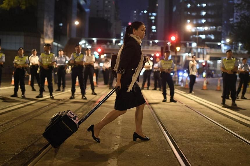 A pedestrian crosses a street alongside security personnel during ongoing pro-democracy protests Hong Kong on Oct 13, 2014. -- PHOTO: AFP