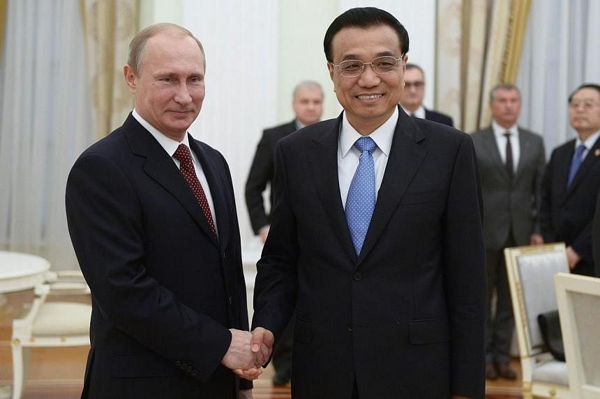 Russia's President Vladimir Putin (left) shakes hands with China's Prime Minister Li Keqiang during their meeting at the Kremlin in Moscow on Oct 14, 2014. -- PHOTO: AFP