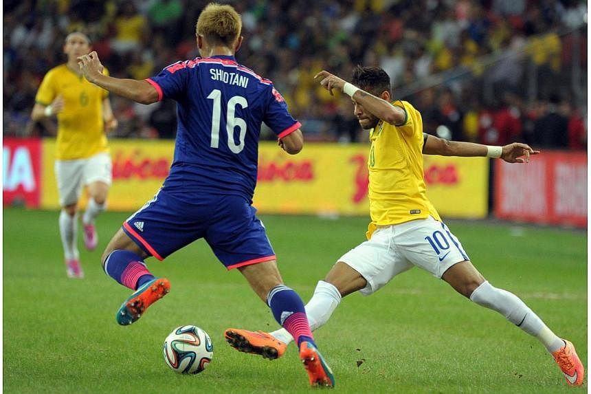 Japan's Shiotani Tsukasa (left) and Brazil's forward Neymar compete for the ball during their friendly football match at the National Stadium in Singapore on Oct 14, 2014. -- PHOTO: AFP