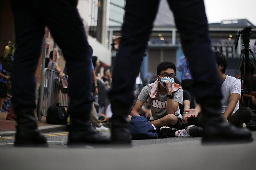 Pro-democracy protesters sit facing policemen as the block an area near the government headquarters building in Hong Kong on Oct 14, 2014. -- PHOTO: REUTERS