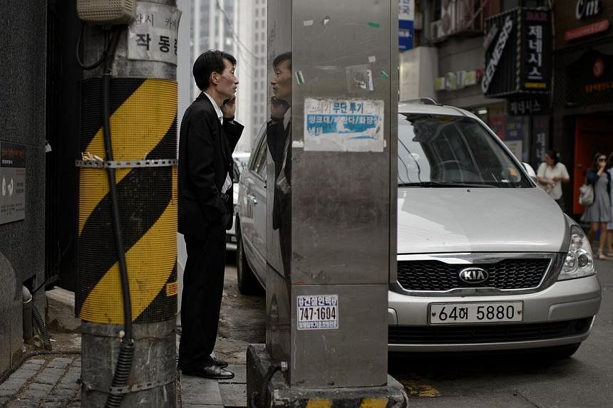 A man talks on a mobile phone in an alleyway in Seoul. South Korea's central bank has cut its benchmark interest rate to the lowest level since 2010. -- PHOTO: AFP&nbsp;