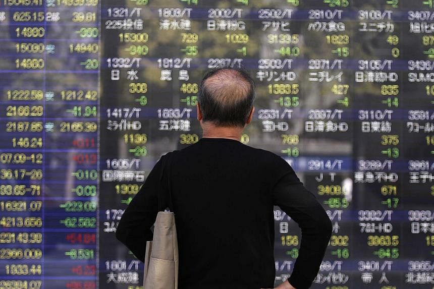 A pedestrian looks at an electronic board showing various stock prices outside a brokerage in Tokyo, Japan. -- PHOTO: REUTERS