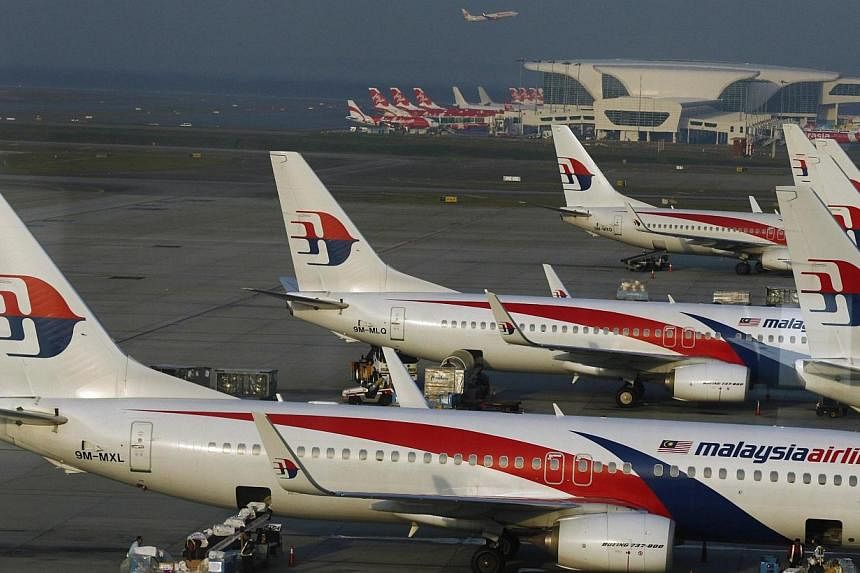 Ground crew work among Malaysia Airlines planes on the runway at Kuala Lumpur International Airport (KLIA) in Sepang, in this July 25, 2014 file photo.&nbsp;Malaysian Airline System Bhd (MAS), the loss-making airline hit by two separate jet disasters