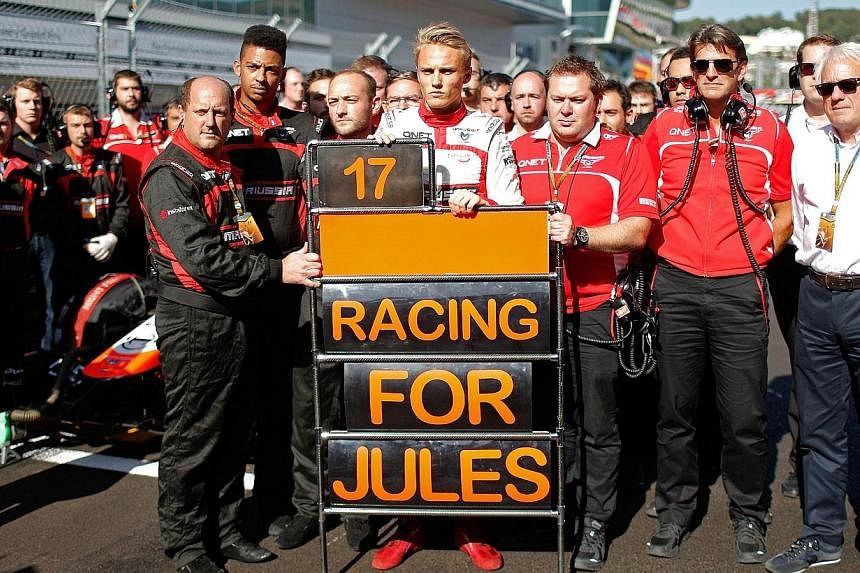 British Formula One driver Max Chilton (centre) of Marussia F1 Team and his team members stand in respect for French Formula One driver Jules Bianchi of Marussia F1 Team at the Sochi autodrom circuit in Sochi on Oct 12, 2014.&nbsp;The Marussia Formul
