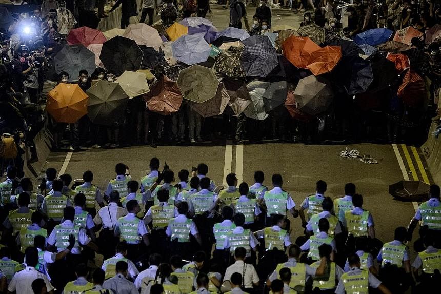 Police forces march toward pro-democracy protesters during a standoff outside the central government offices in Hong Kong on Oct 14, 2014. -- PHOTO: AFP