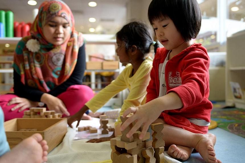 Ng Le Qi (right) playing with wooden blocks in a block play experience being facilitated by Farhana Kamal Beck (left), English teacher at The Caterpillar's Cove, a childcare centre which NTUC First Campus runs in Ngee Ann Polytechnic. -- PHOTO: ST FI