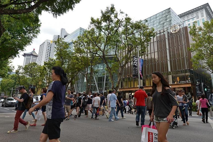 Pedestrians cross the street along the Orchard Road shopping area in Singapore. Retail sales have went up by 5.4 per cent in August compared to last year. -- ST PHOTO: CAROLINE CHIA