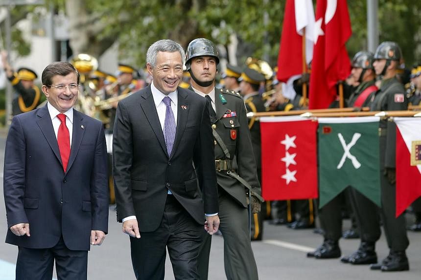 Prime Minister Lee Hsien Loong and Turkey's Prime Minister Ahmet Davutoglu (left) review the honour guard during a welcoming ceremony in Ankara, Turkey on Oct 14, 2014. -- ST PHOTO:&nbsp;CHEW SENG KIM